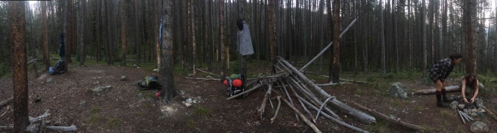 Panoramic view of a forest campsite with two people