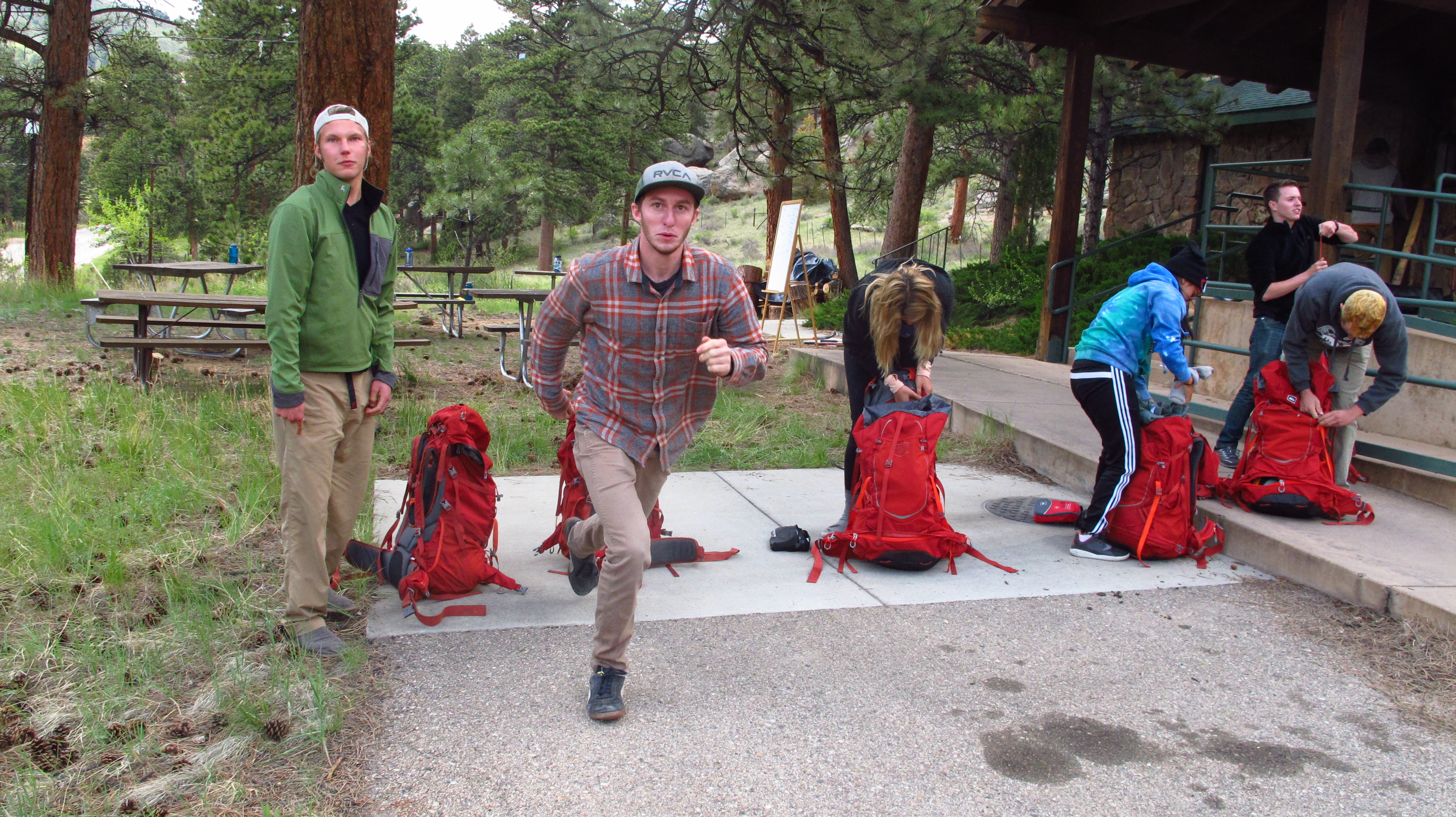 Group of trainees preparing a red backpack for hiking