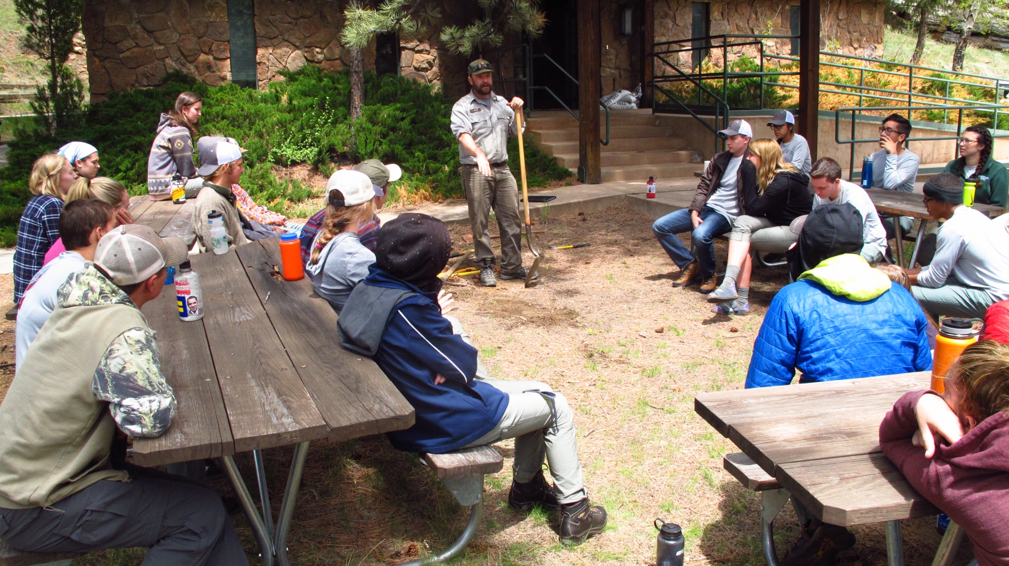 Ranger discussing towards a group of trainees sitting on benches