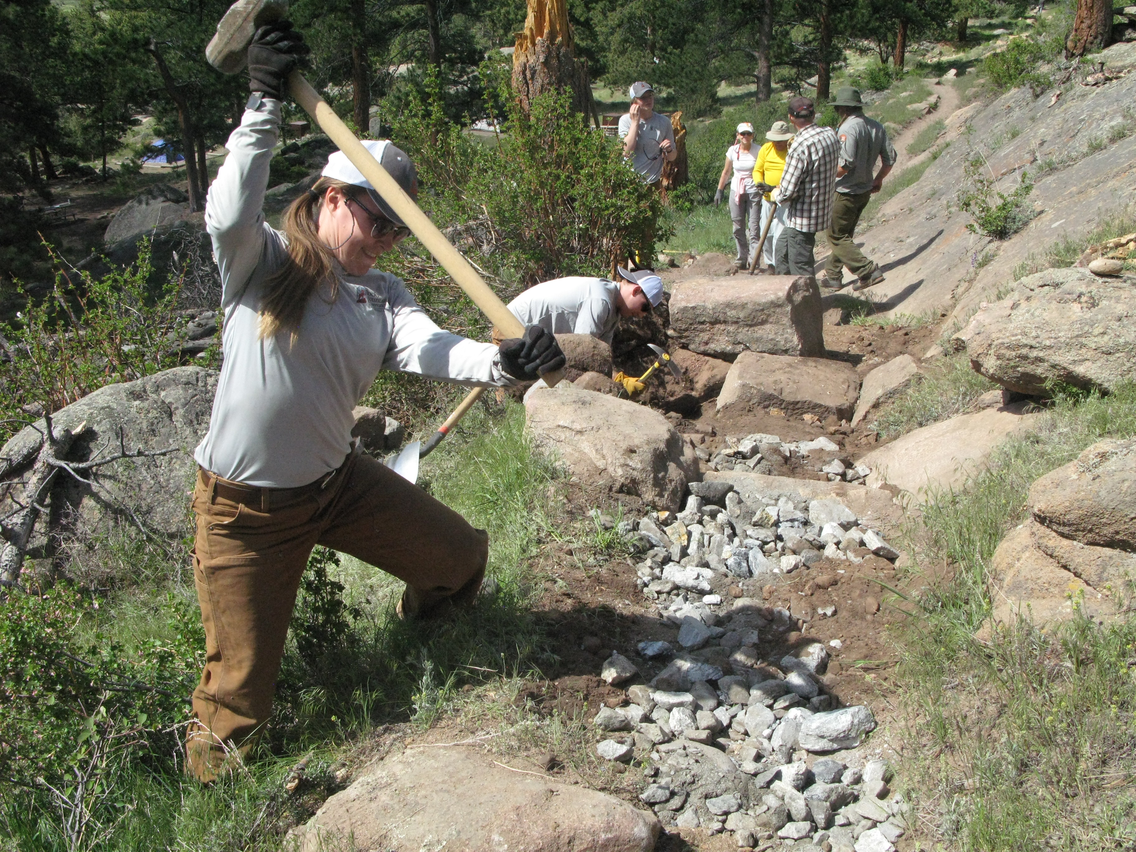 Woman holding a mallet to smash small rocks along a newly created stairs