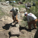 A group of men working on a rocky area.