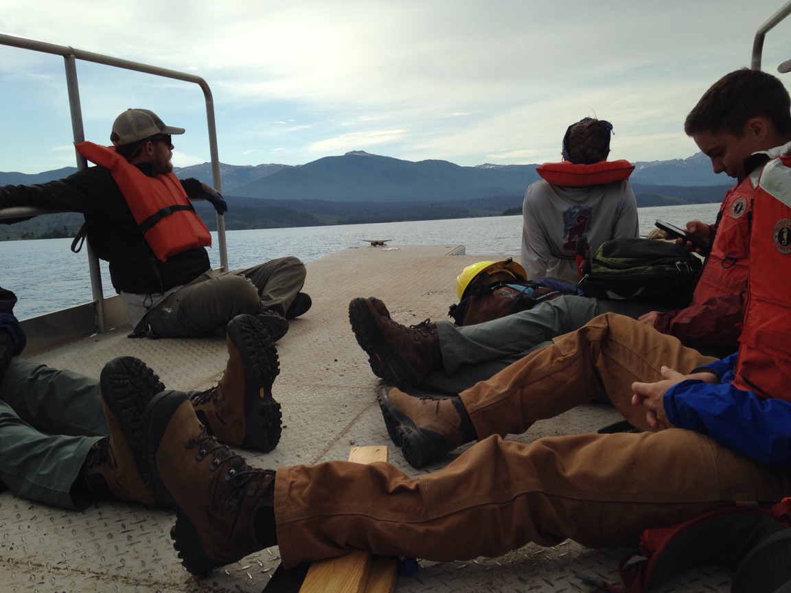 People sitting and relaxing on a boat deck with mountain and lake views.