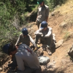 A group of people sitting on the side of a trail.