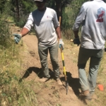 Two men with shovels on a dirt path.