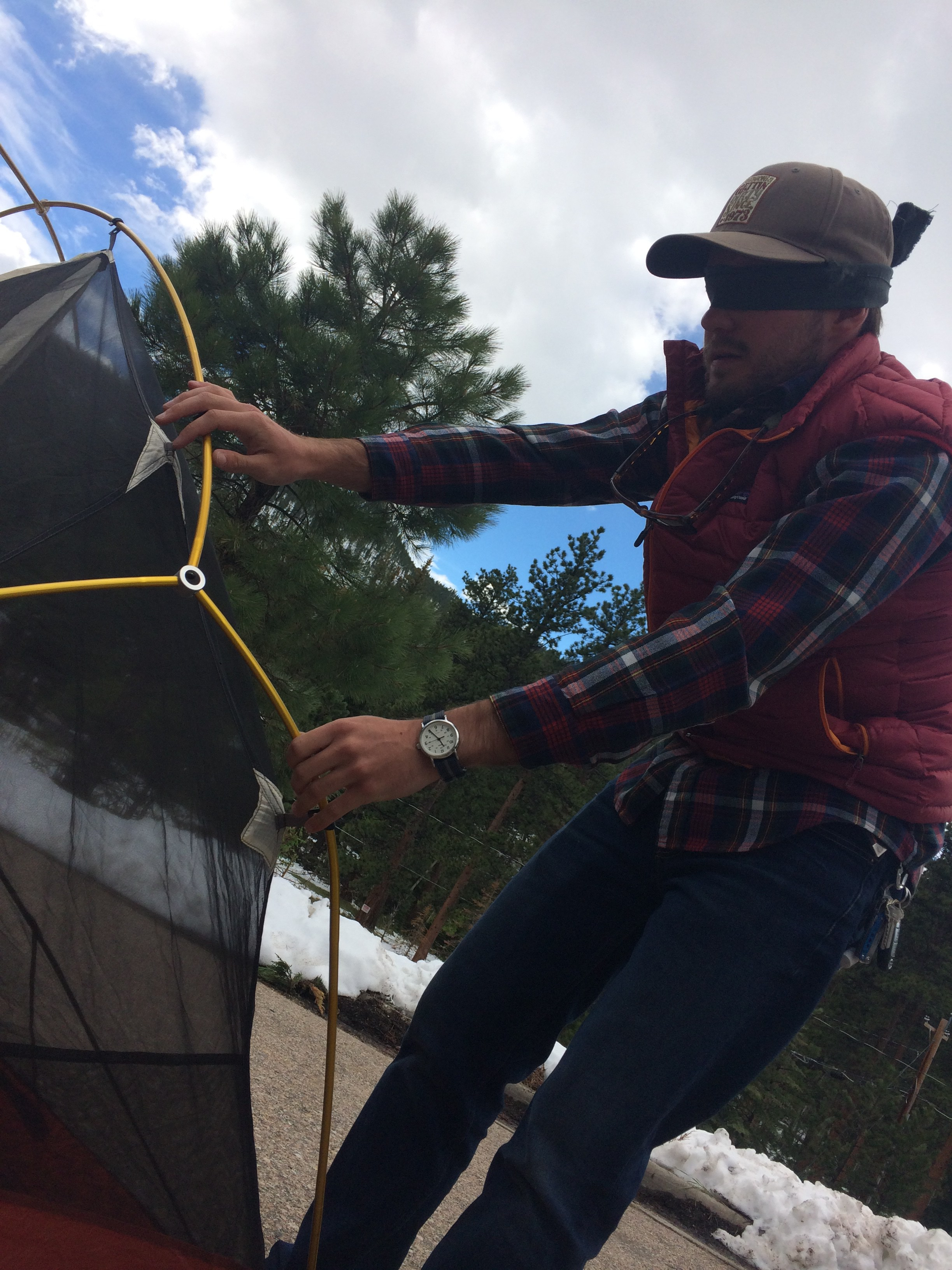 A mansetting up a tent in a wooded area