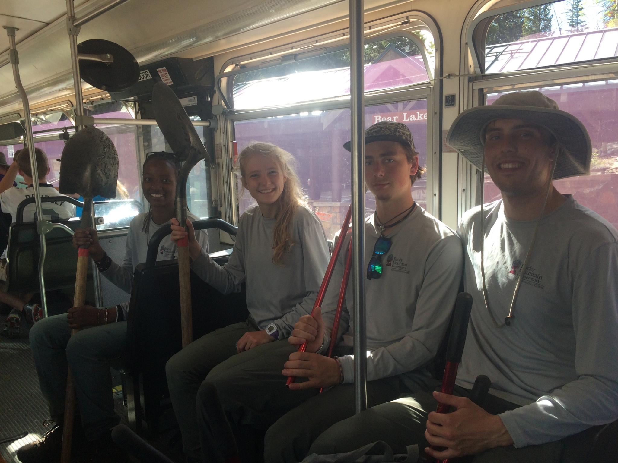 Four young adults smiling on a bus