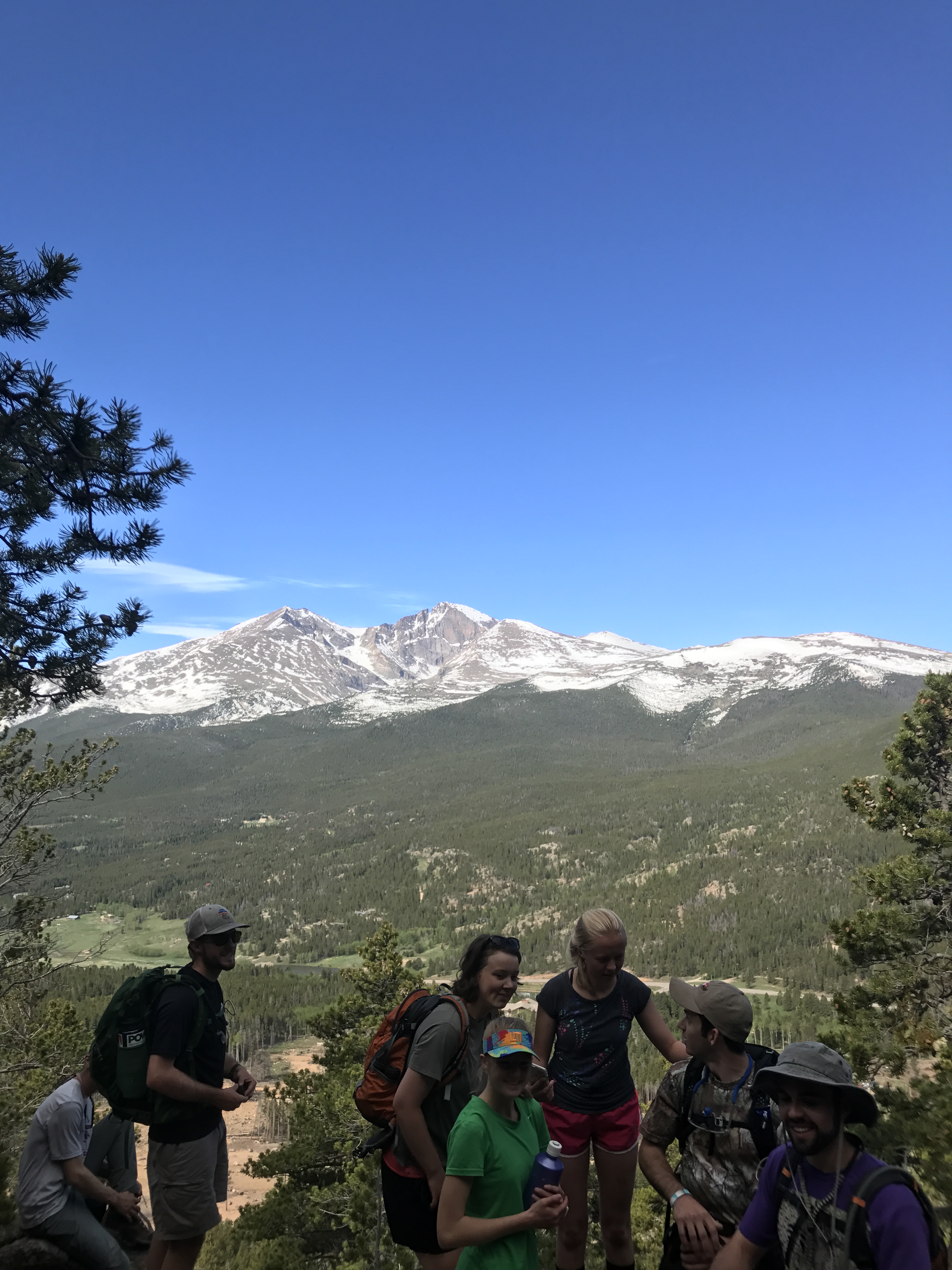 A group of hikers with backpacks enjoying a conversation on a mountain overlook