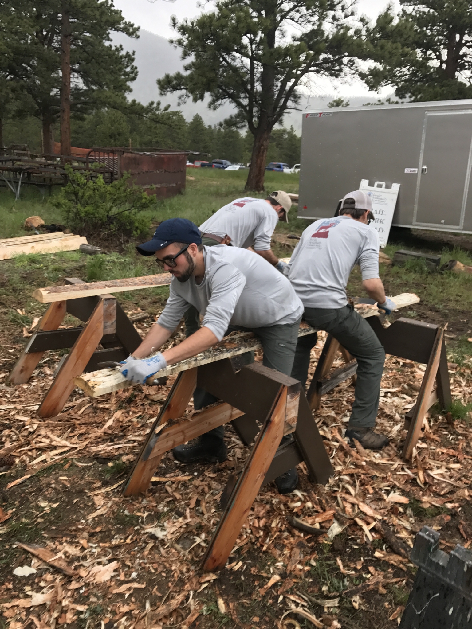 Three men assembling wooden structures outdoors