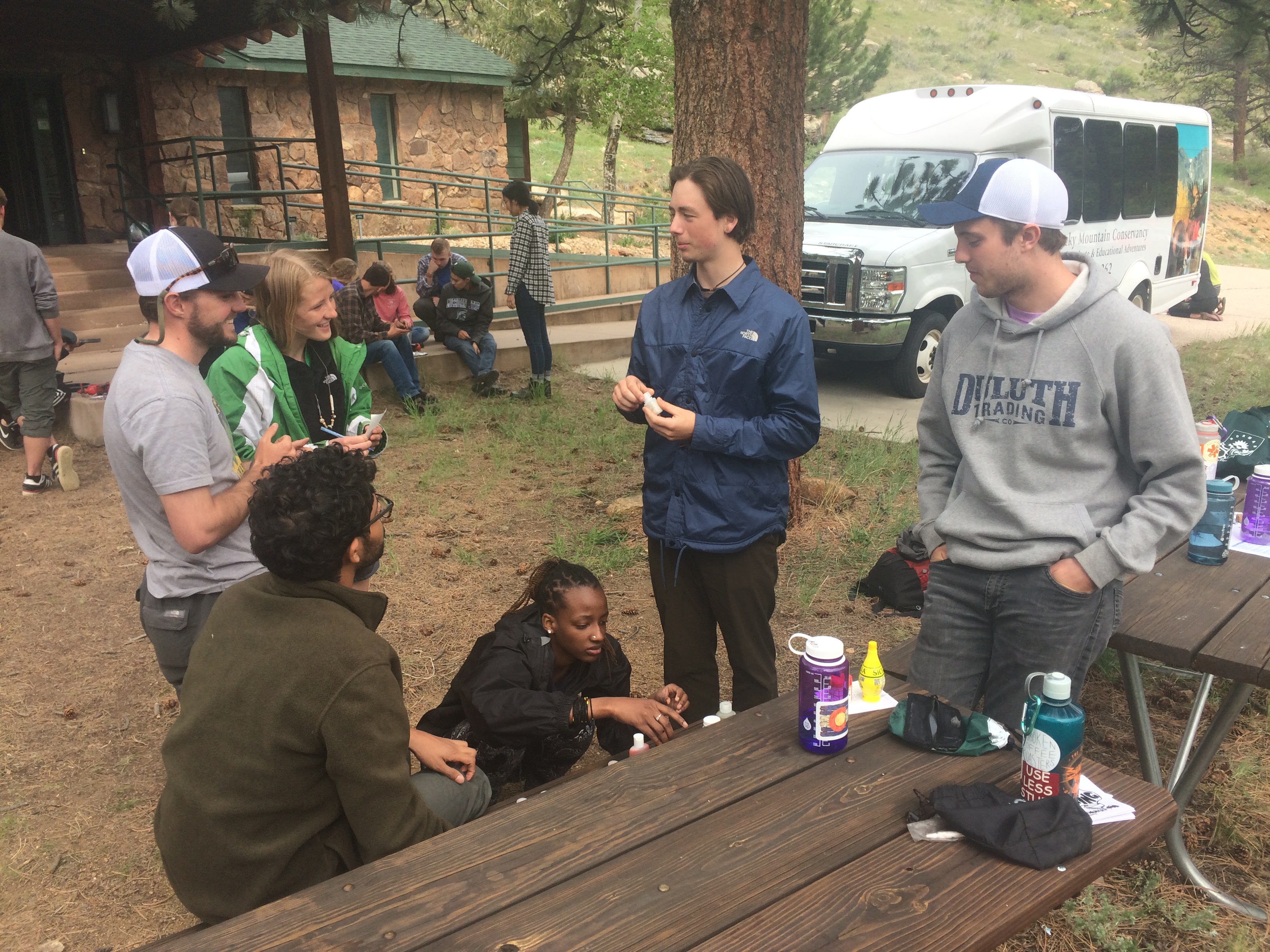 Group of people chatting around a picnic table in a park