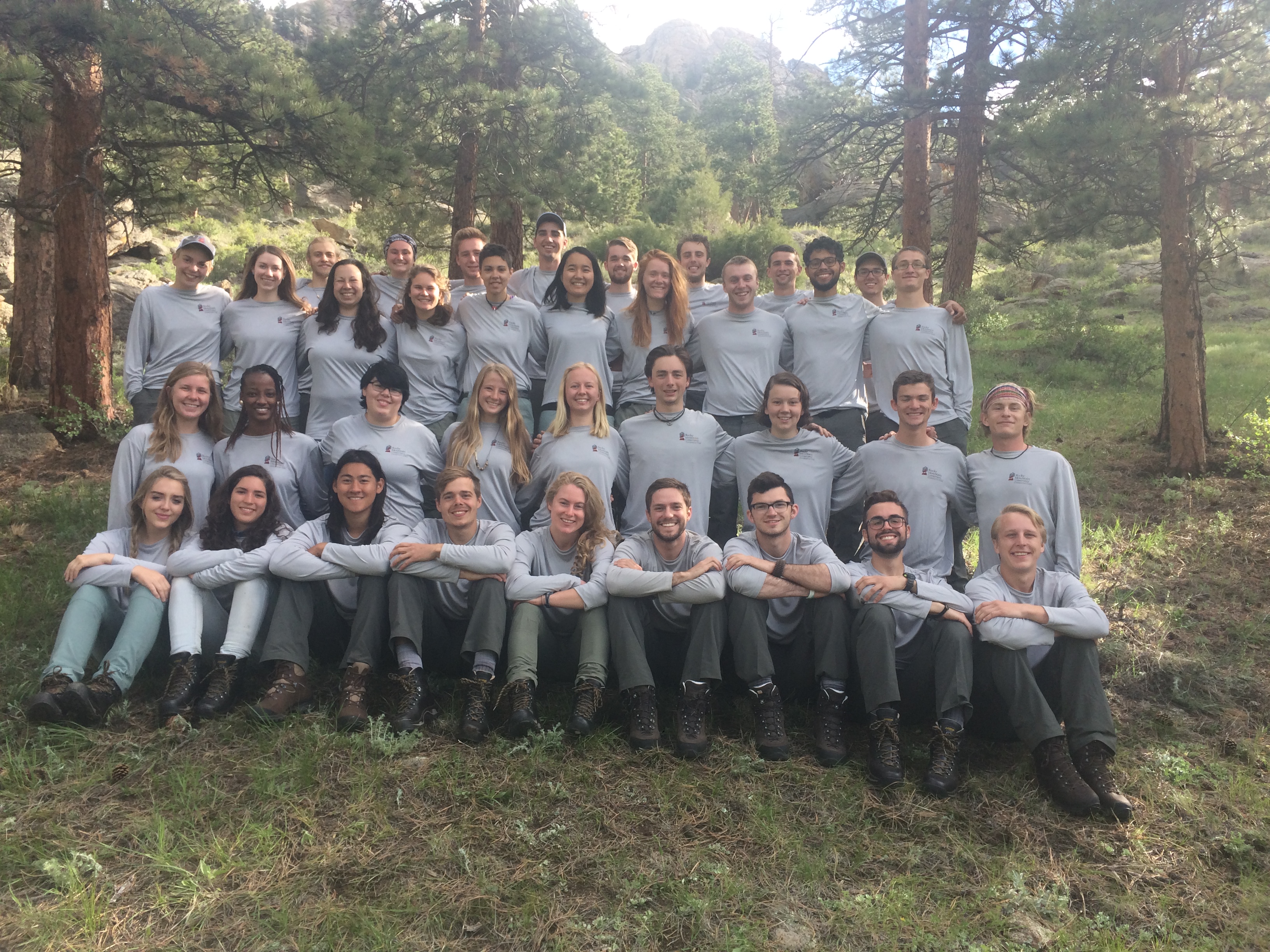 Group of young adults in gray uniforms posing outdoors