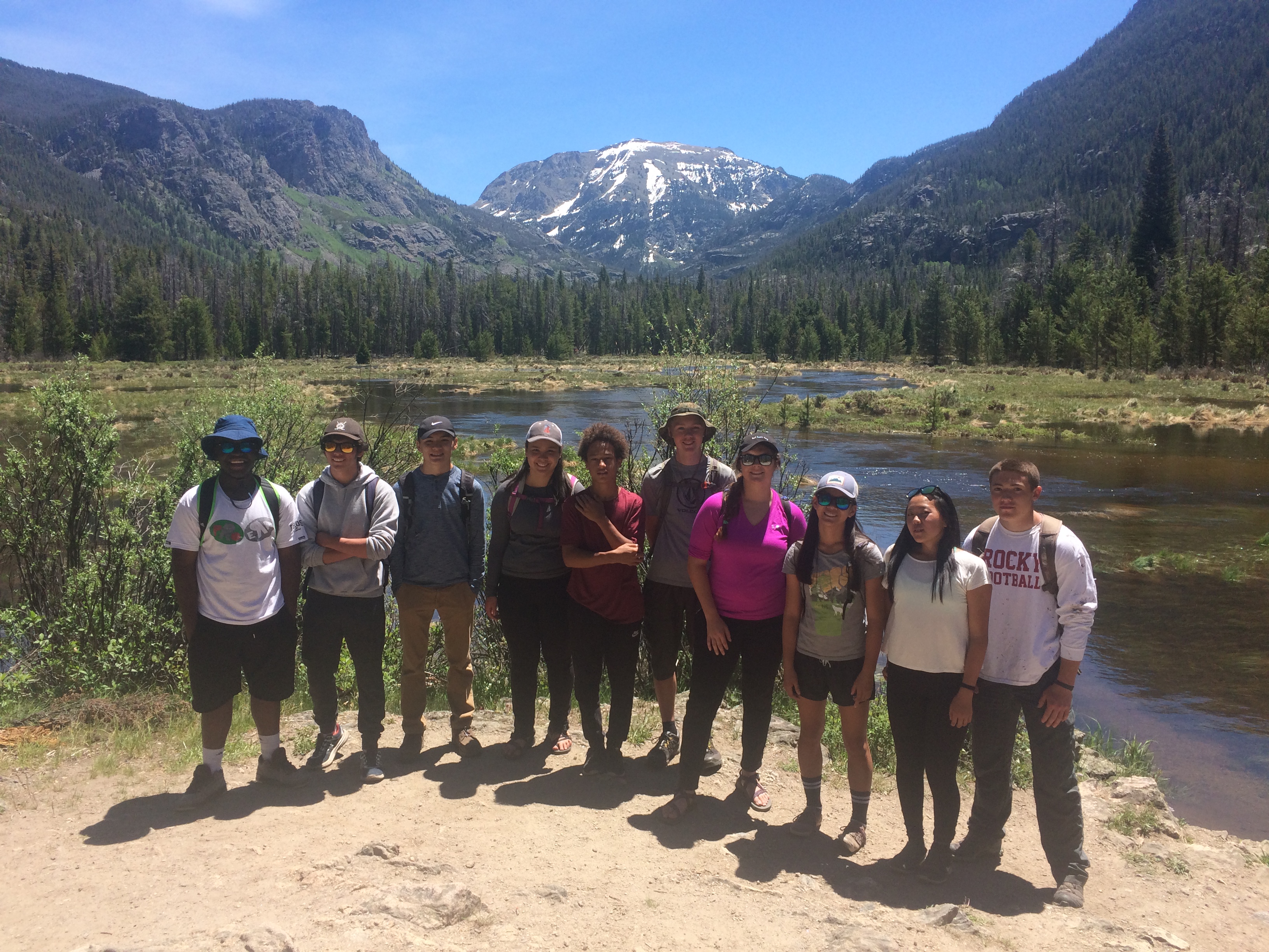 Group of hikers posing in front of a scenic mountain and forest landscape