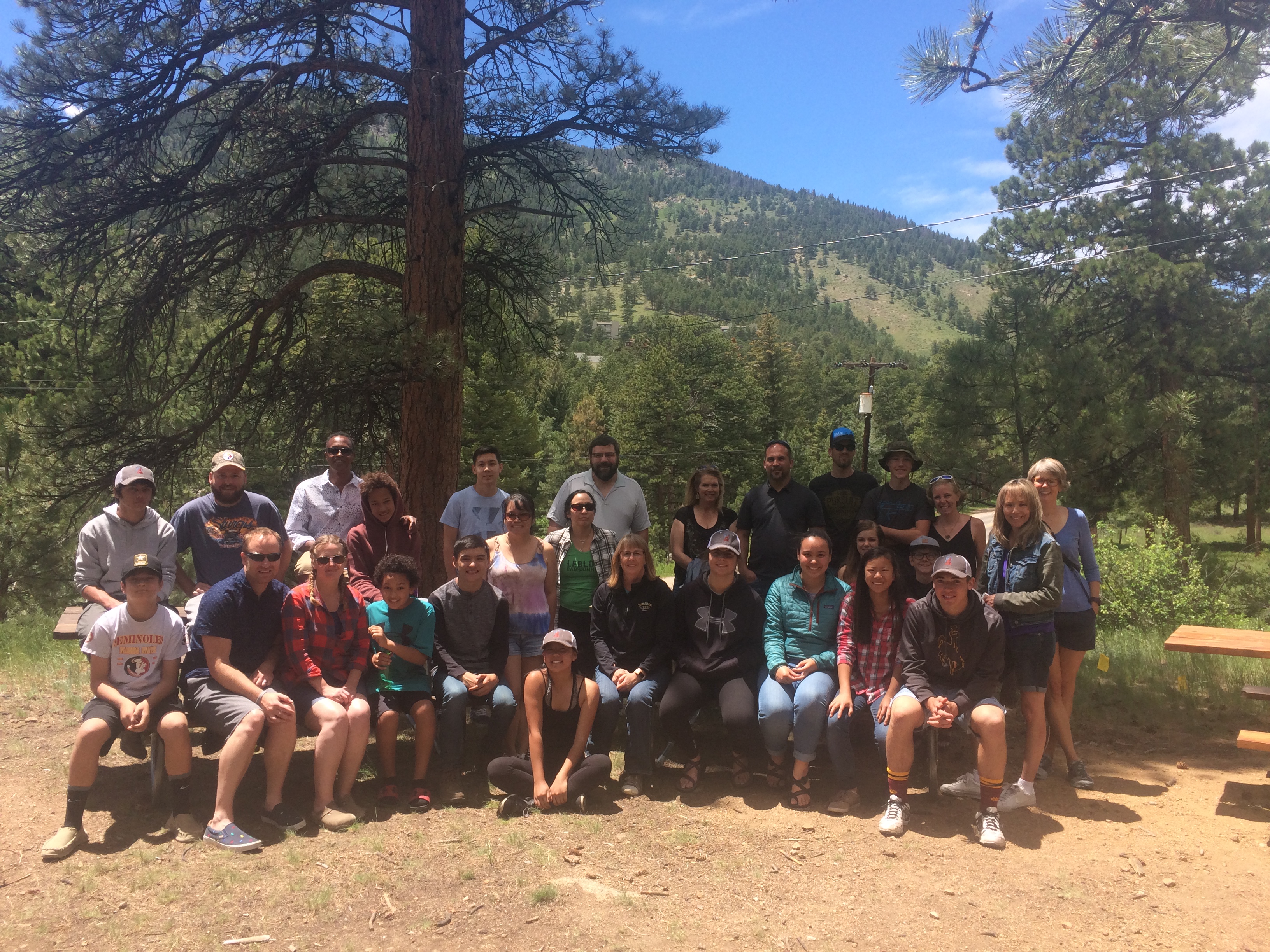 Group of people posing for a photo in a forested area with pine trees