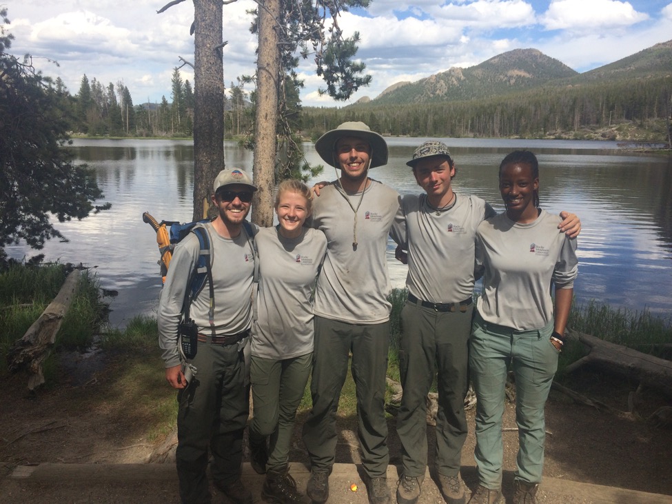 Five park rangers smiling standing by a lake