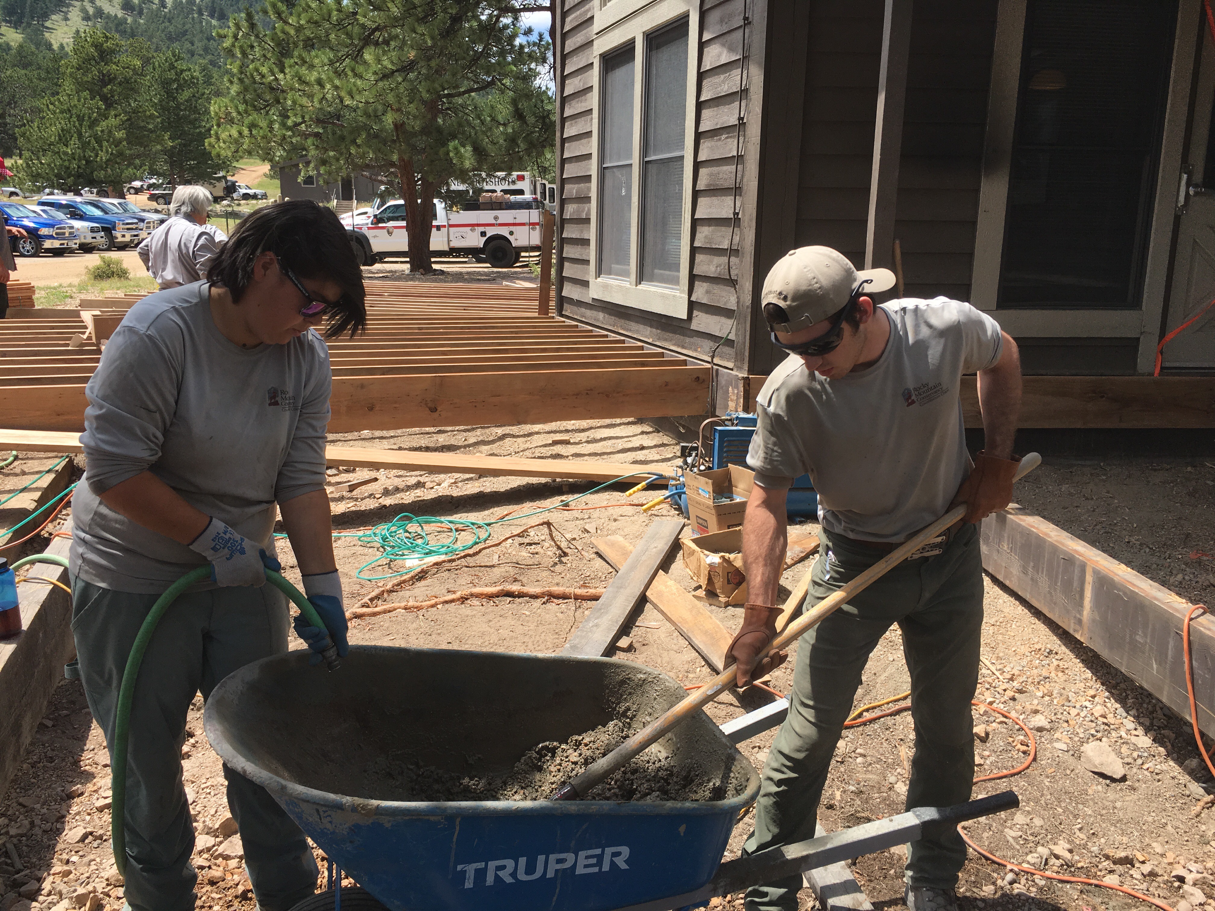 Two construction workers using shovels to mix concrete