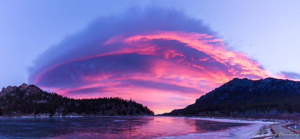 A colorful cloud over a lake at sunset.