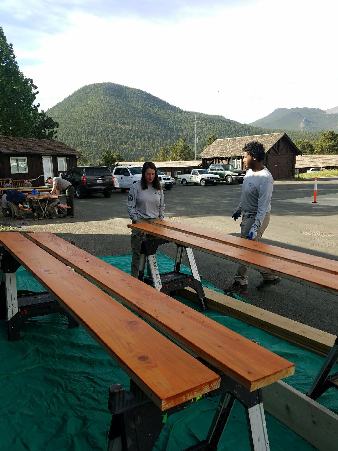 Two people staining wooden planks on outdoors