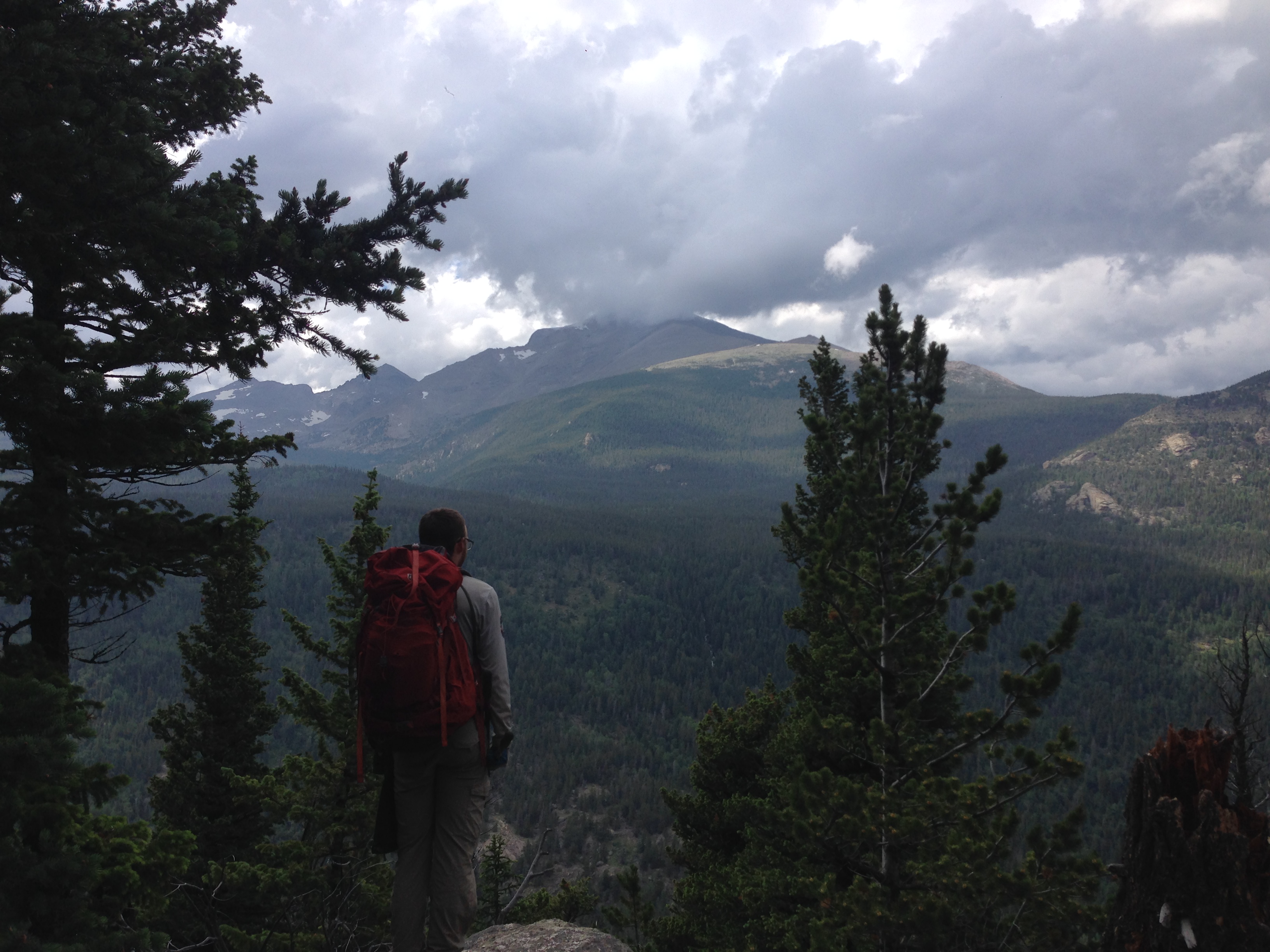 A person with a backpack stands on a rocky overlook