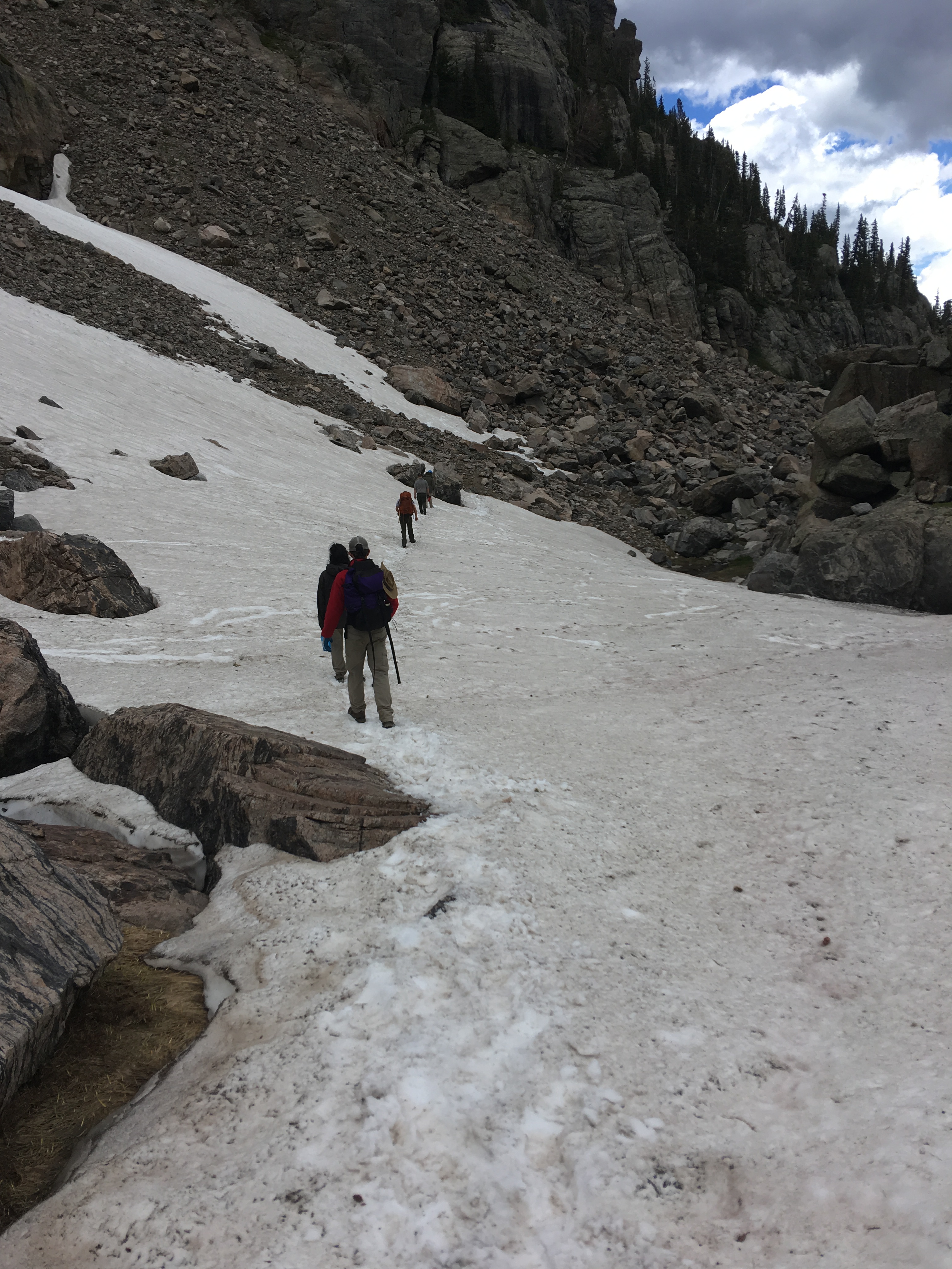 Hikers with backpacks ascending a snowy mountain trail