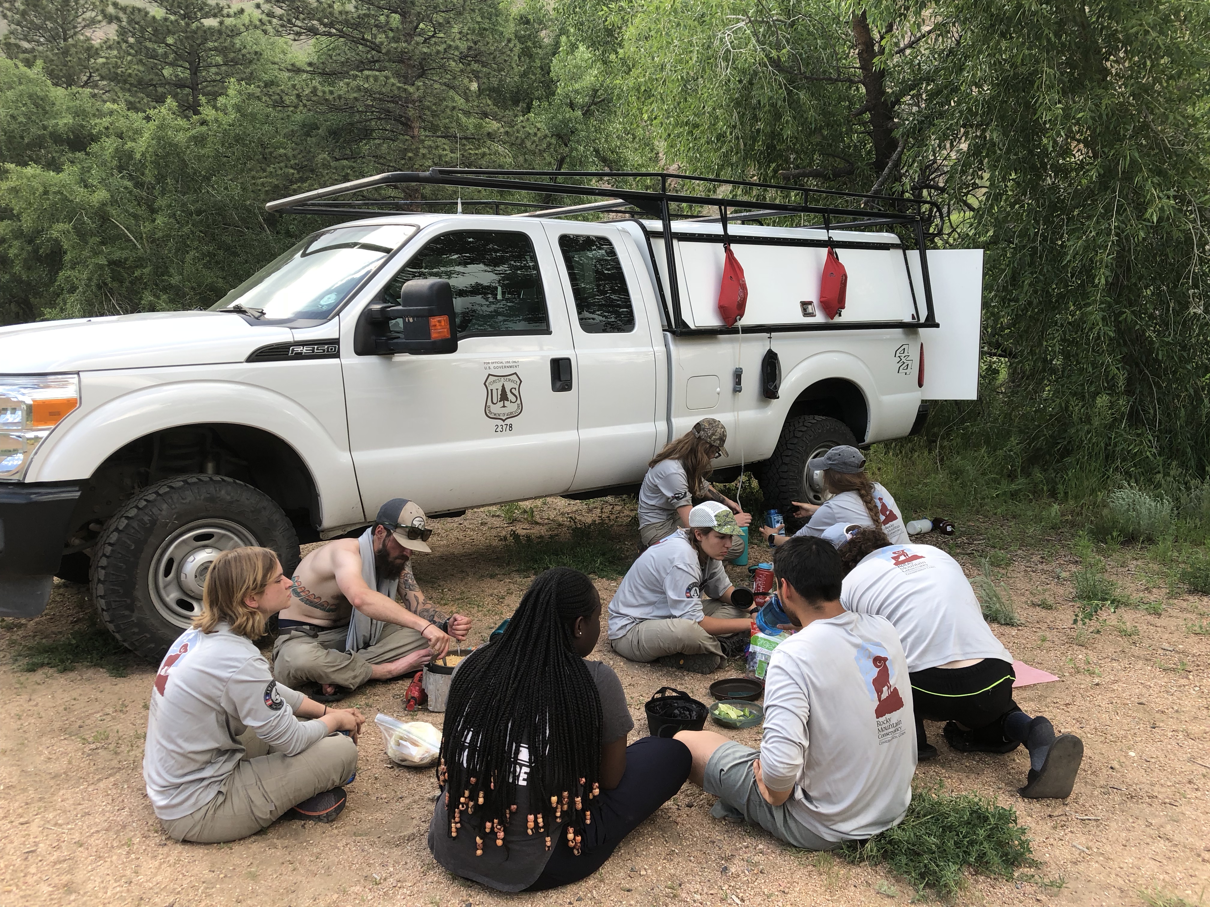 A group of forest service workers eating near a white service truck