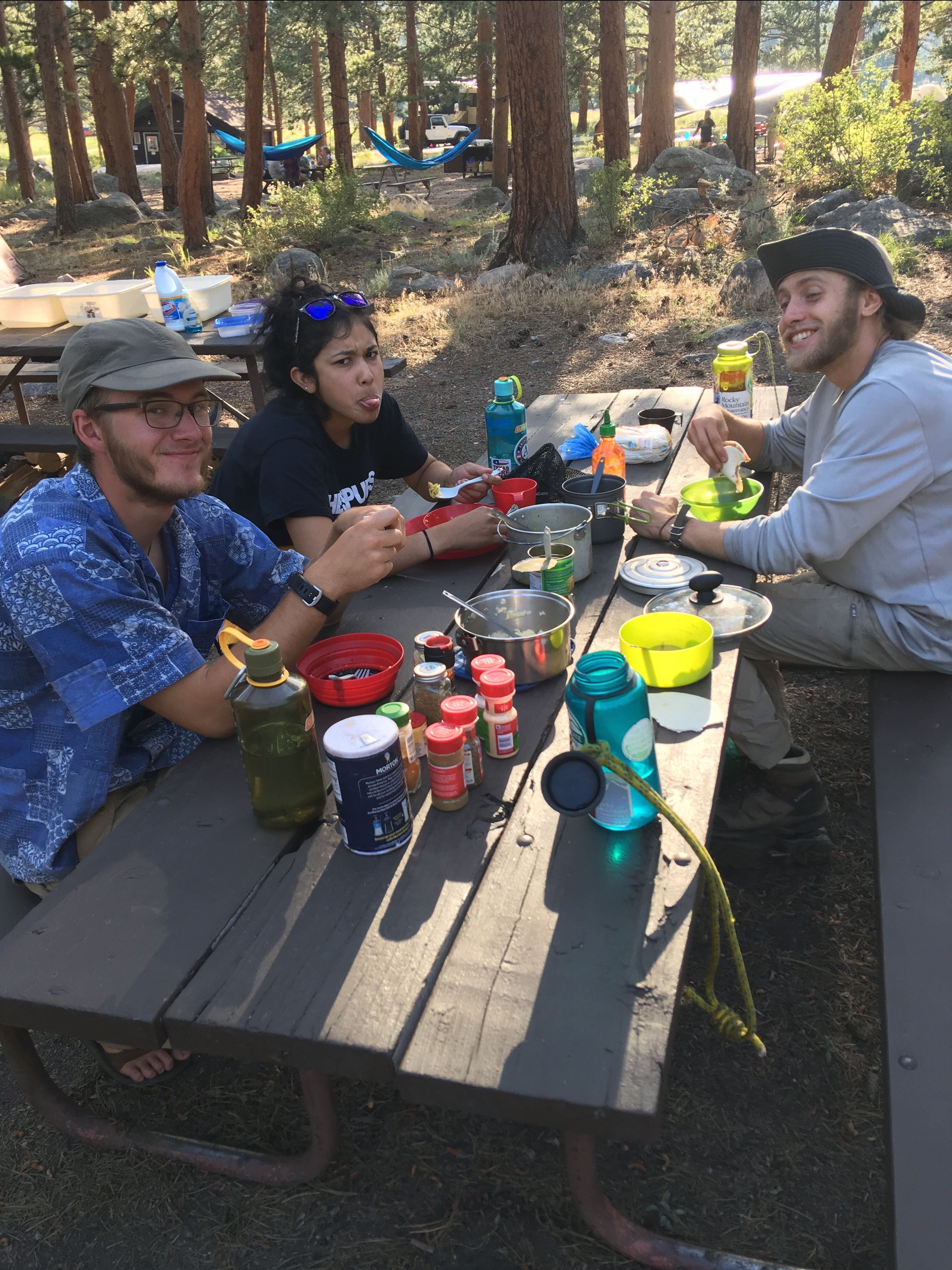 Three friends enjoying a meal at a campsite