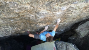 A man is climbing on a rock in a cave.