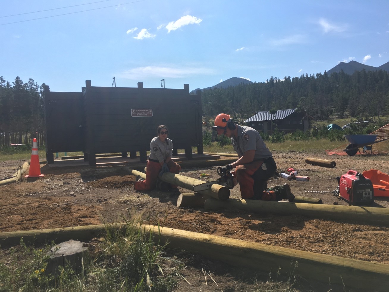 Two workers using a chainsaw to cut logs