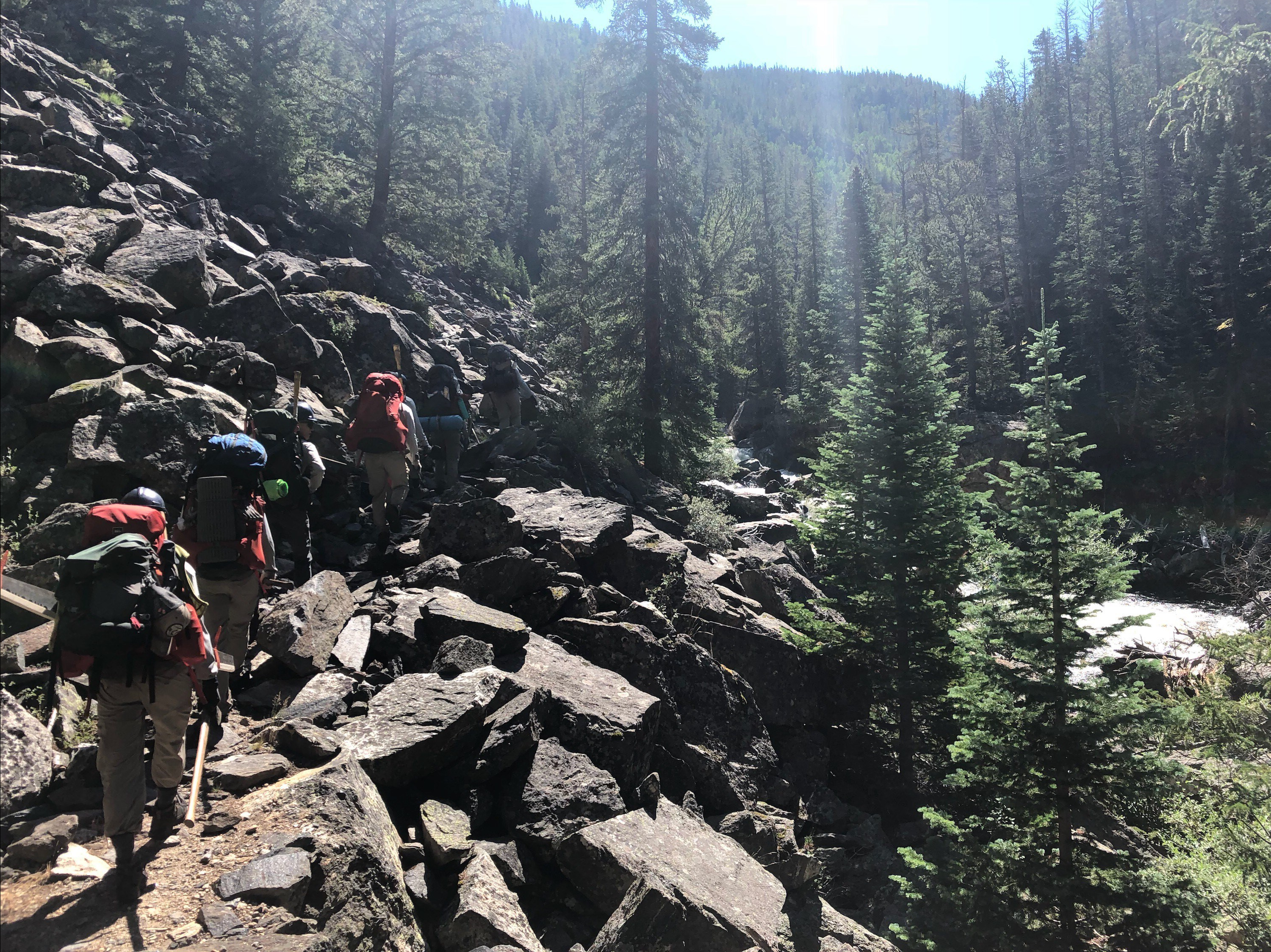 Hikers with backpacks trekking along a rocky mountain trail