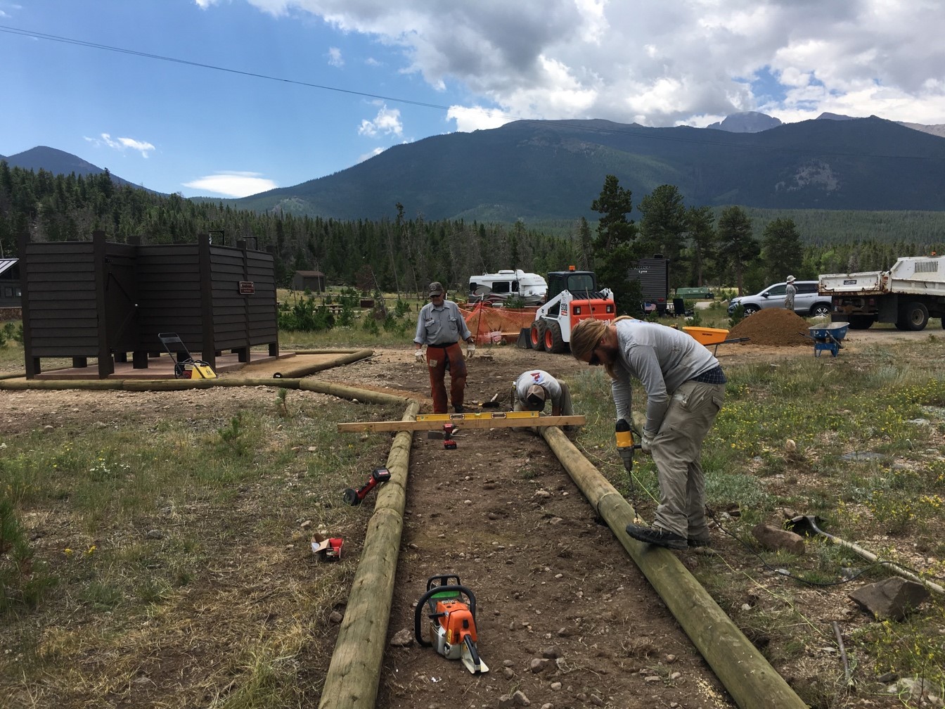 Two people working on a construction site with tools and materials