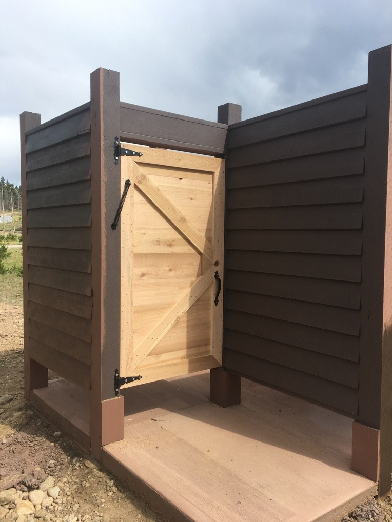 Wooden outdoor shower enclosure with an open wooden door