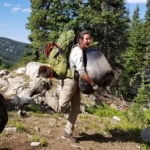 A man carrying a large backpack on a rocky trail.