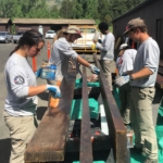 A group of people working on a wooden bench.