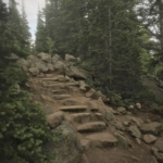A trail leading up to a rocky area with trees in the background.