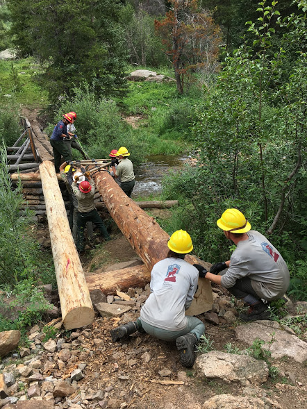 Group of workers creating a trail across a water stream