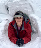 A woman sitting in a snow hole.