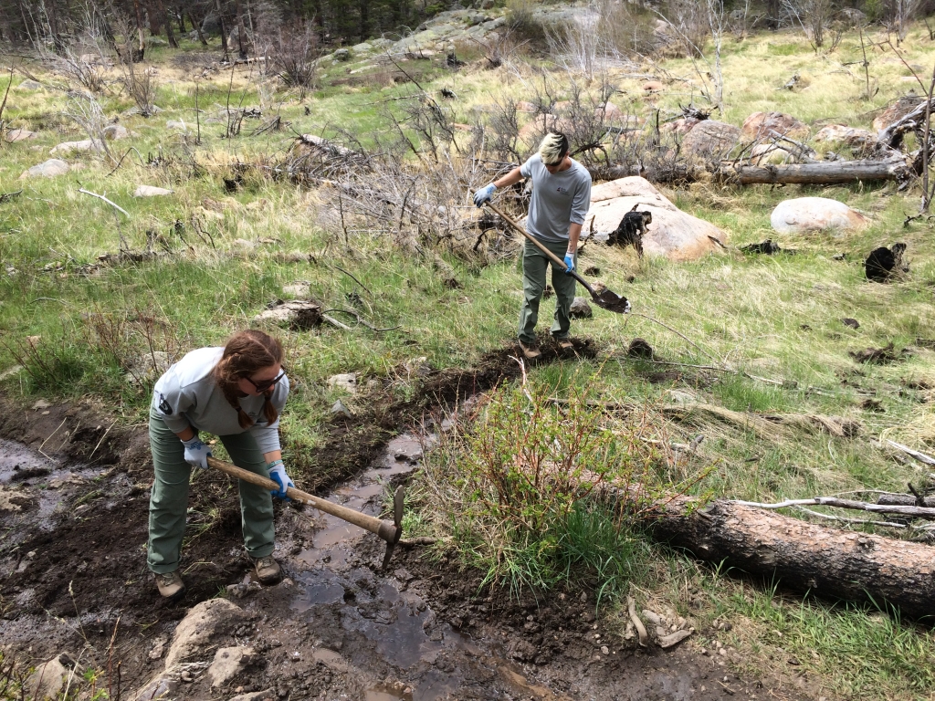 Two people working in a muddy area.