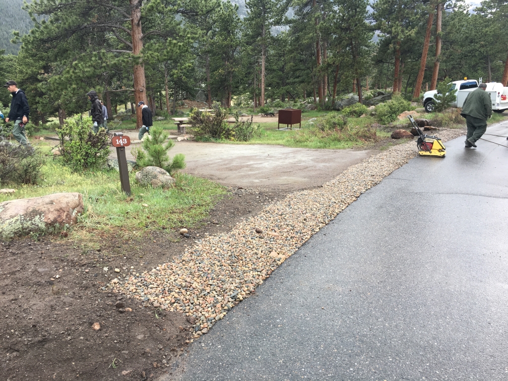 A group of people are walking down a gravel road.