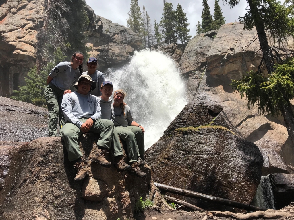 A group of people posing in front of a waterfall.