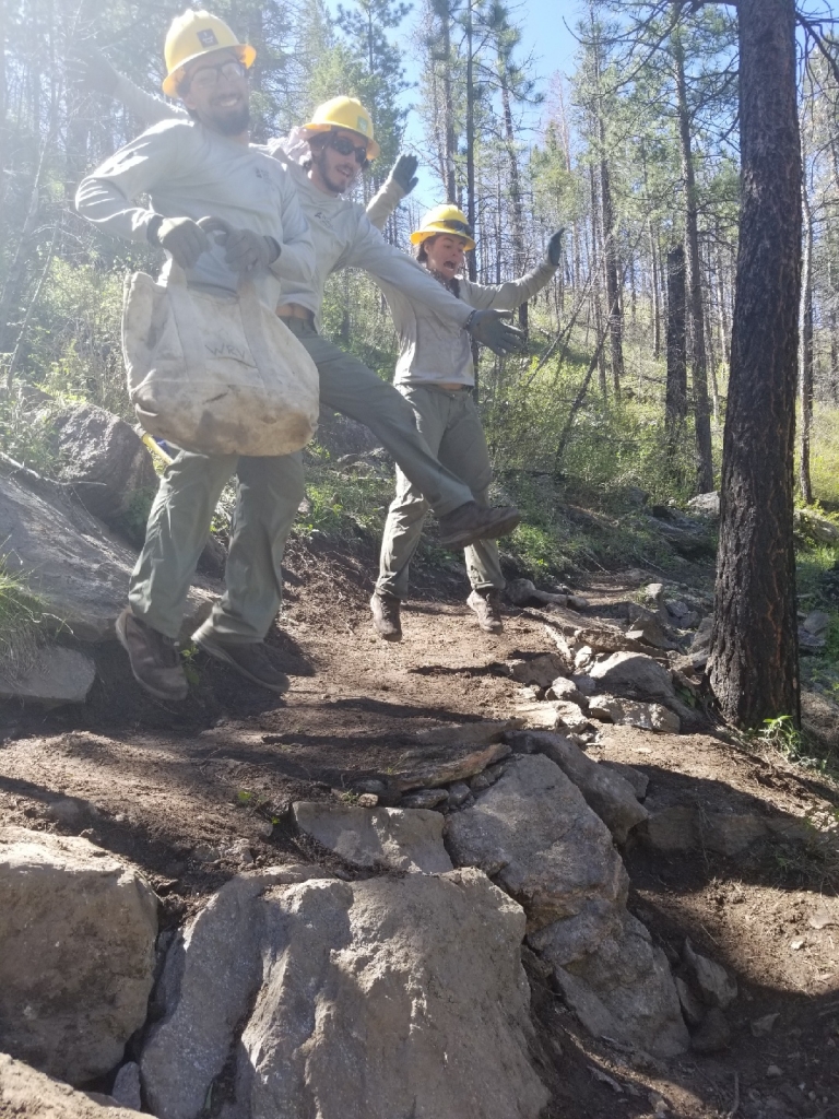 Three people in hard hats running down a rocky trail.