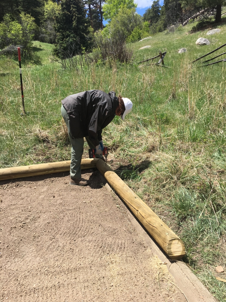 A man working on a wooden fence in a field.