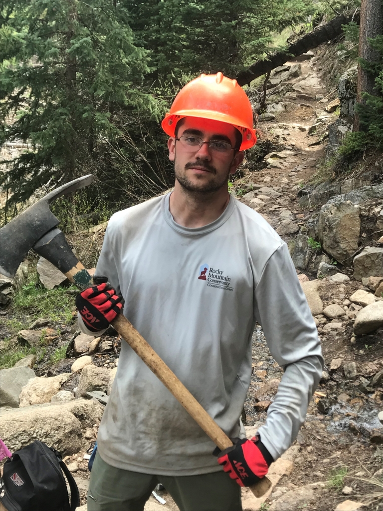 A man holding an ax on a trail.