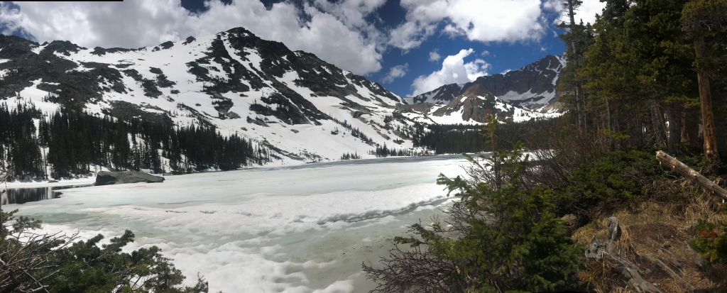 A view of a mountain lake with snow on it.