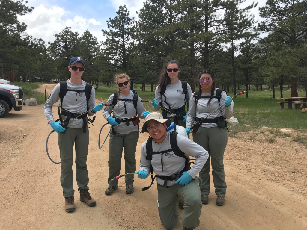 A group of people standing on a dirt road with backpacks.