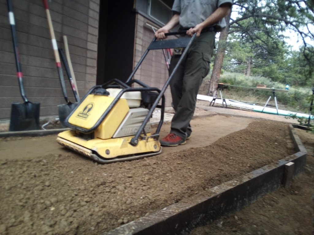 A man is using a machine to smooth out the dirt.