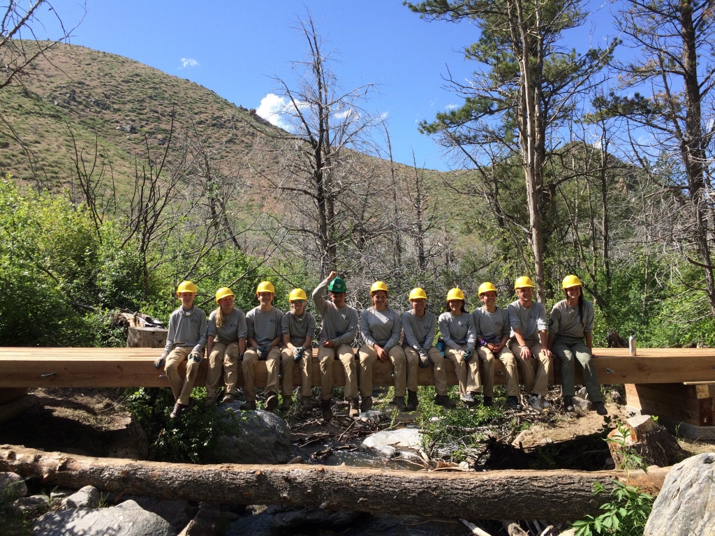 A group of people posing on a wooden bridge.