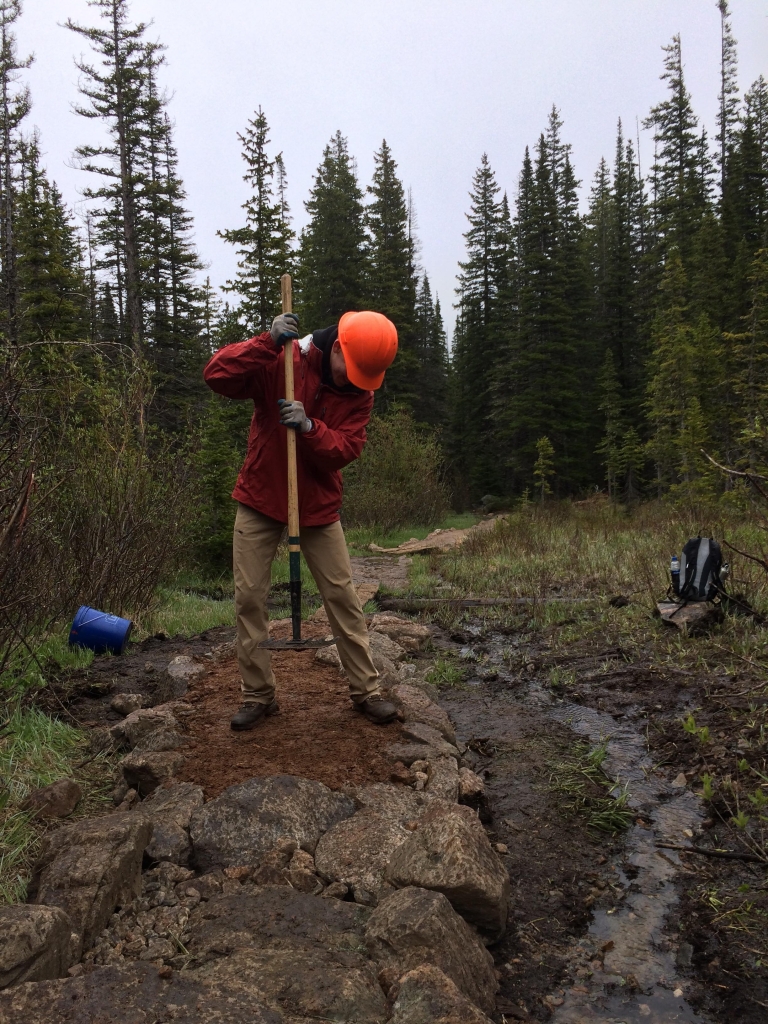 A man working on a trail with a shovel.