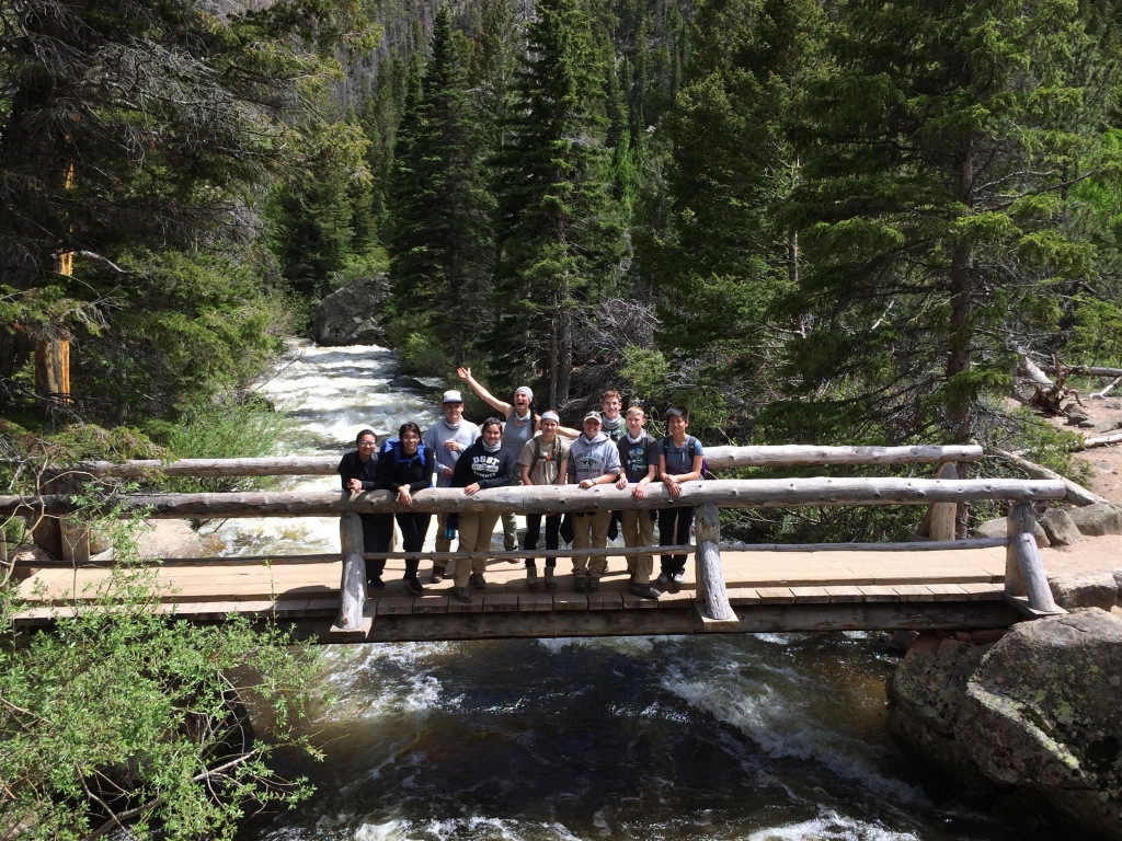 A group of people standing on a wooden bridge.