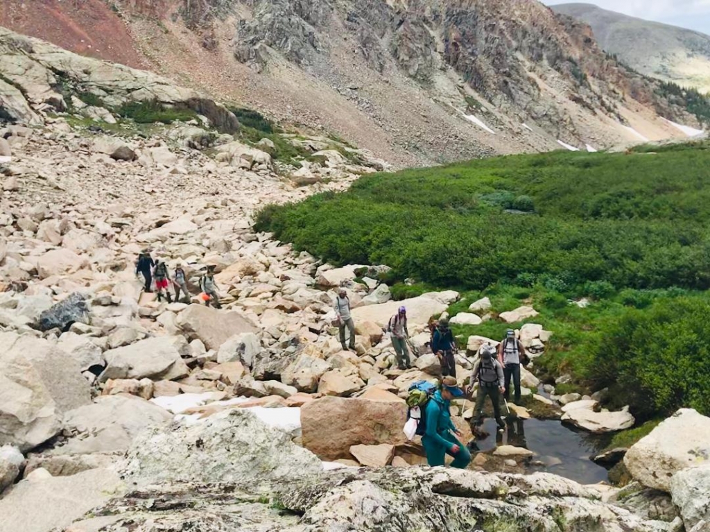 A group of people walking on rocks in the mountains.