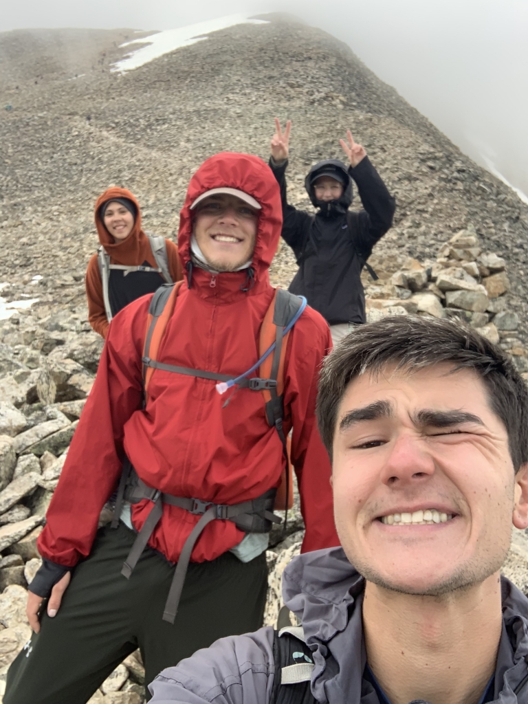 A group of people taking a selfie on top of a mountain.