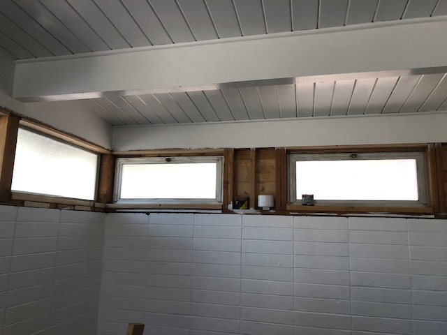A bathroom with white tile and a window.