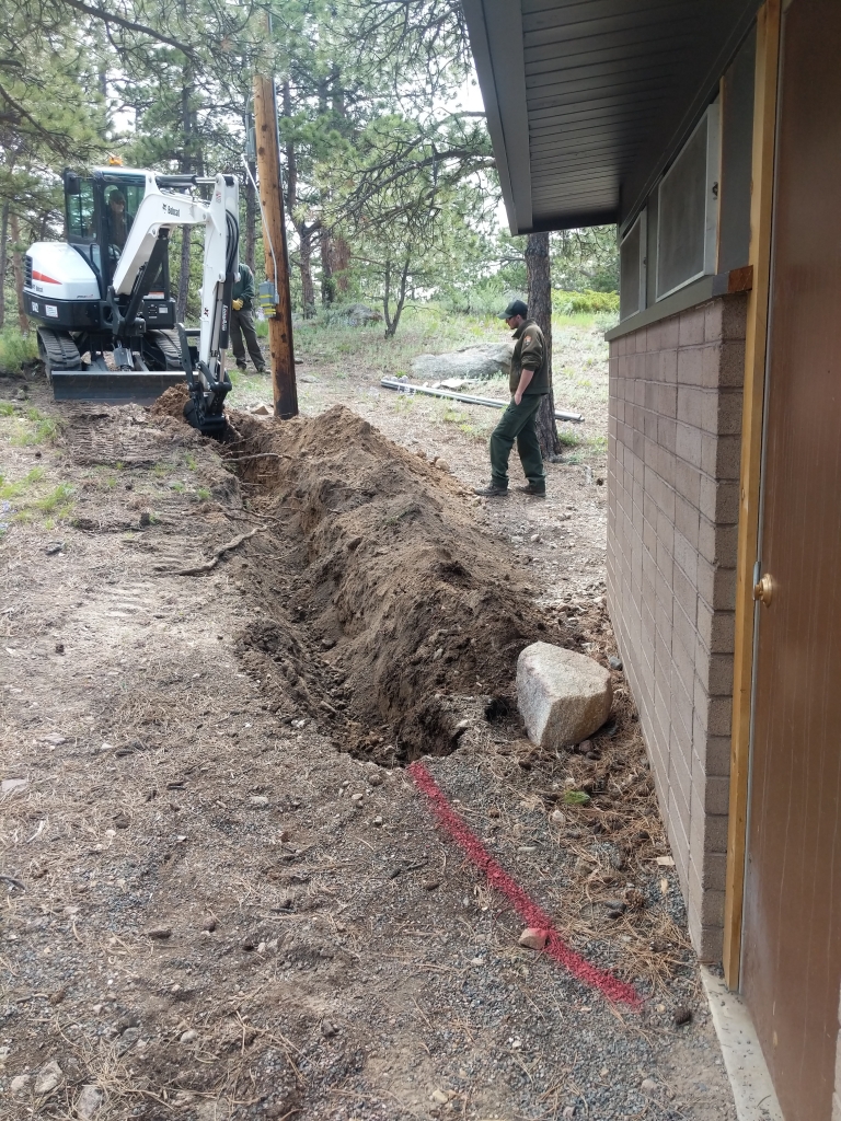 An excavator digging a hole next to a house.